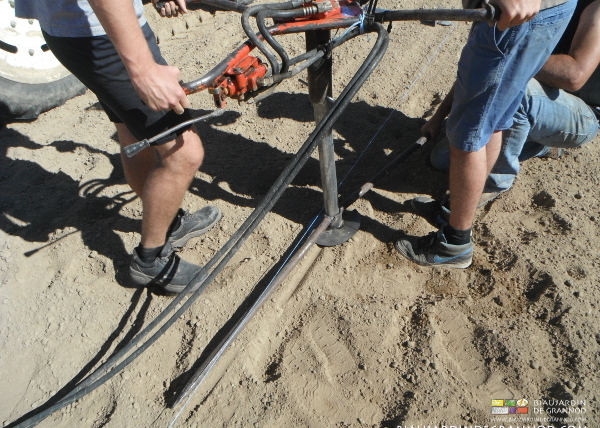 photo des mains et pieds tenant tarière et petits outils pour enfoncer droit l'amarre 