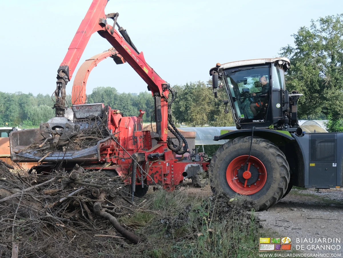 photo de la grue conduite depuis le tracteur qui alimente le tapis d'amenée de la déchiqueteuse
