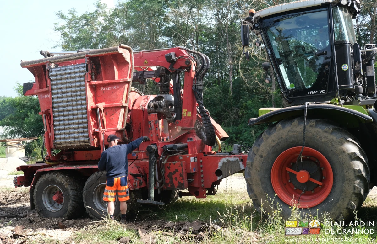 photo du conducteur de la CUMA nettoyant à l'air la déchiqueteuse de sa sciure