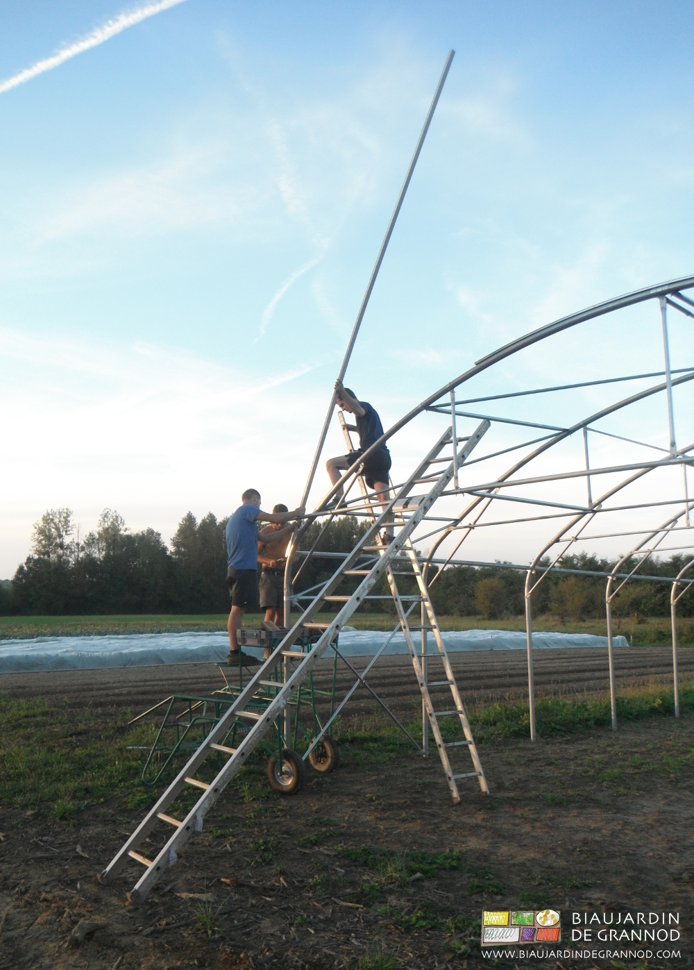 photo de 2 travailleurs forçant pour courber le profil sur l'arceau pendant que le troisième visse