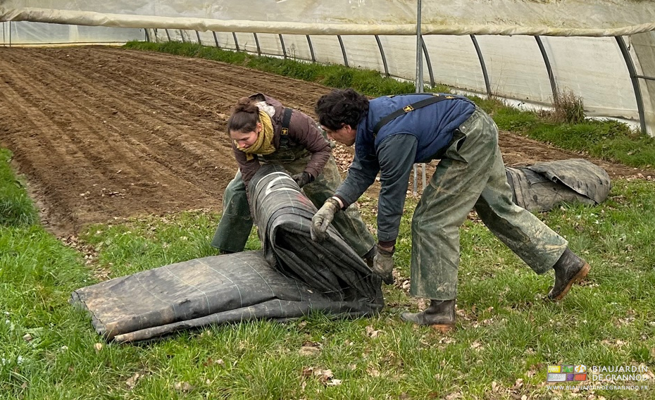photo d'Émilie et Vivien pliant les toiles noires tissées d'occultation devant le tunnel de carotte