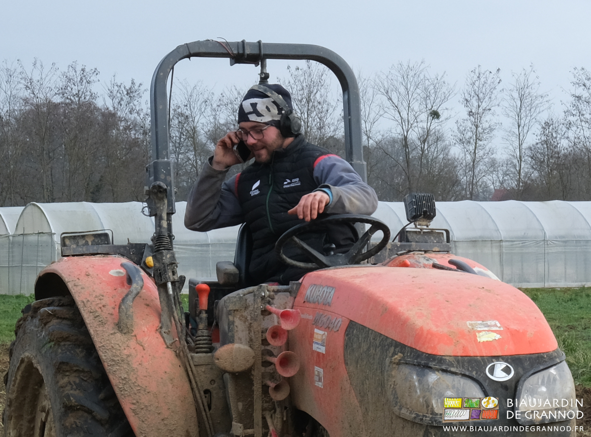 photo de Matthieu buttant des planches au tracteur et téléphonant tout sourire