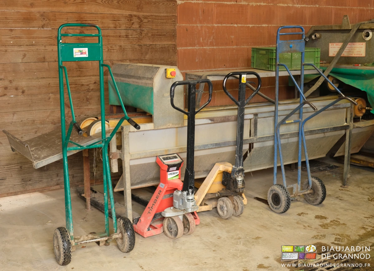 photo des diables à caisses et transpalettes rangés sous la laveuse à poireau