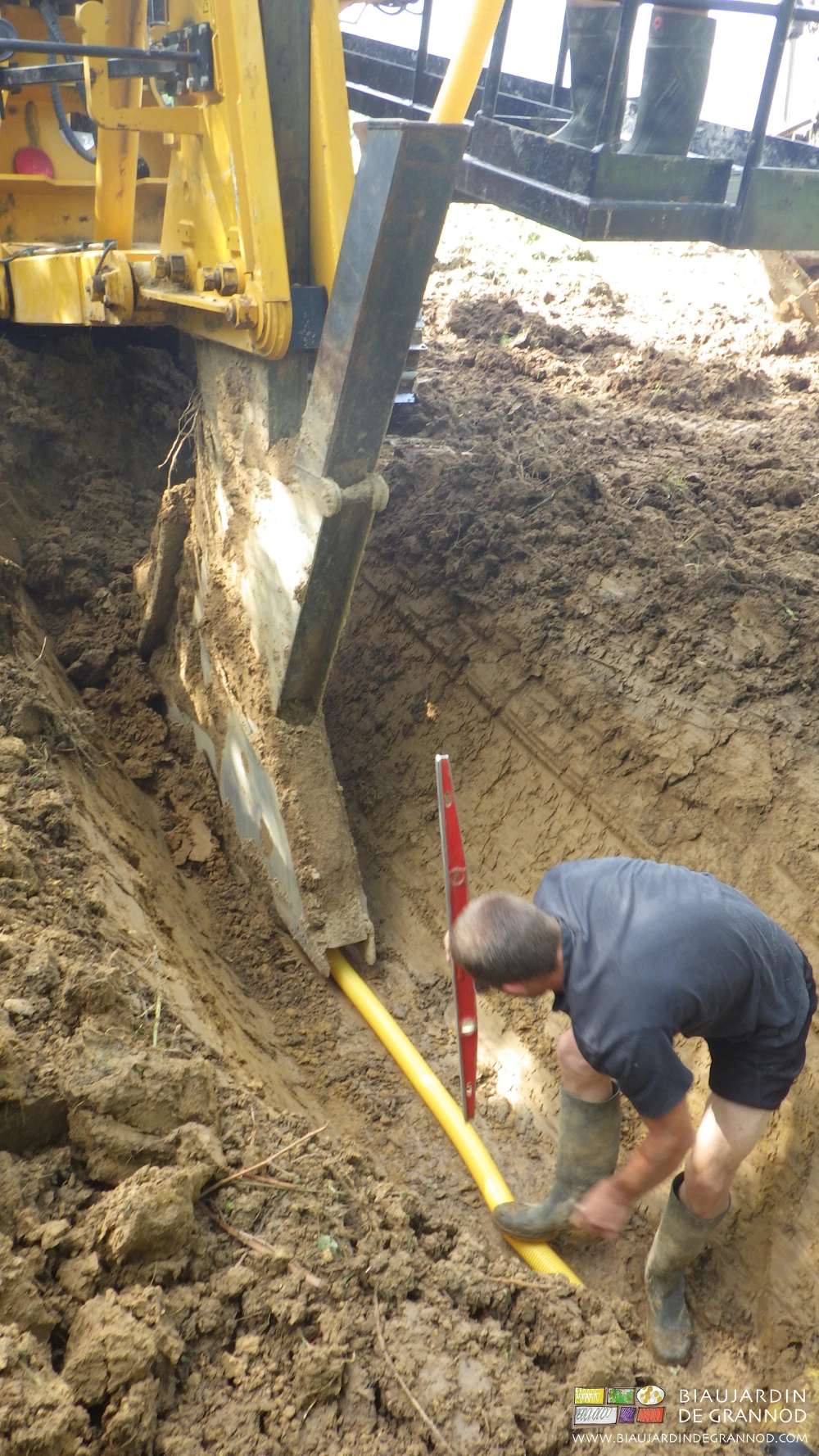 photo du travailleur retenant le drain en fond de tranchée au démarrage du sous-soleur
