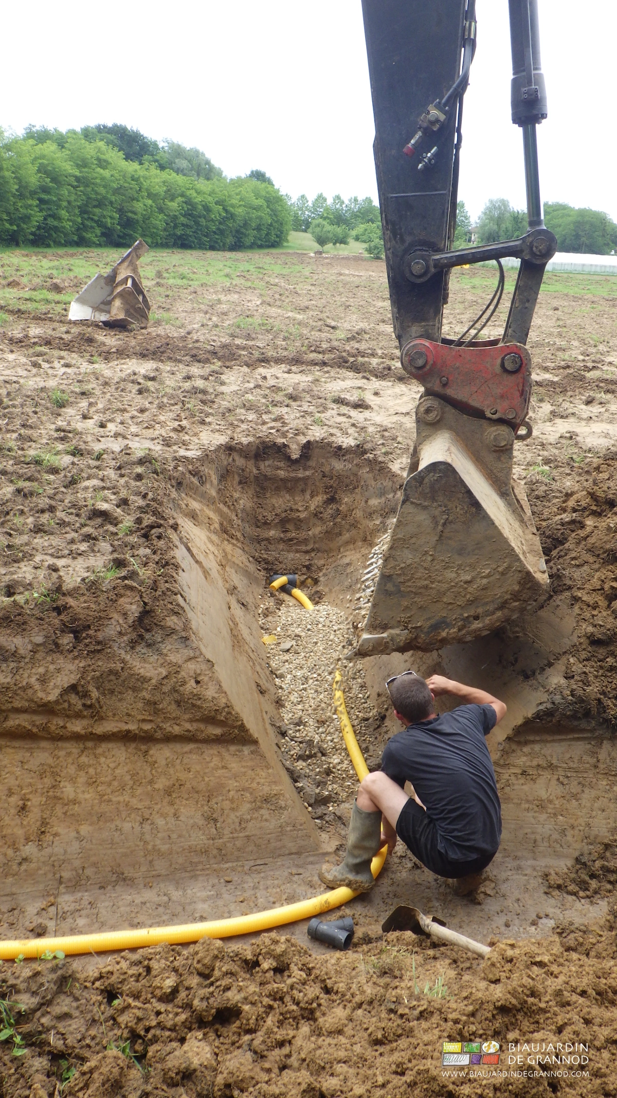photo de cohabitation de godet de pelleteuse et travailleur dans une seule tranchée