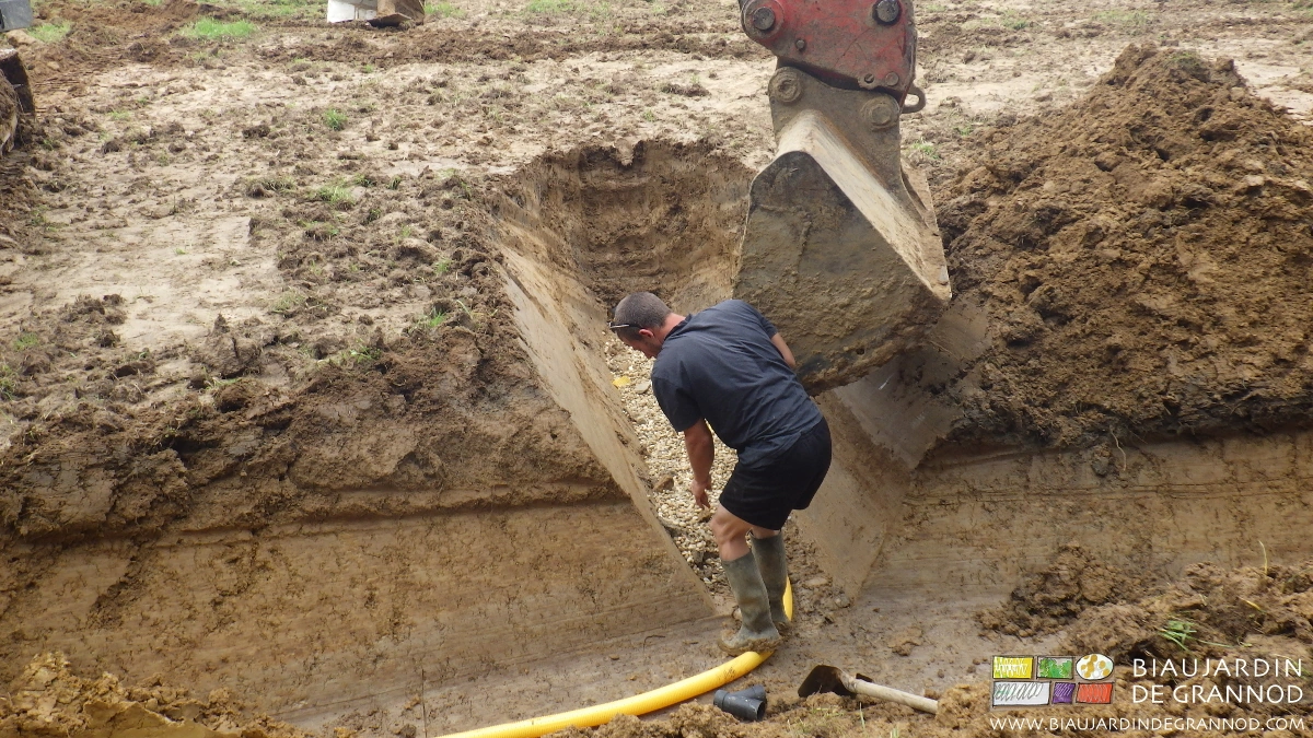 le godet de pelleteuse travaille à toucher celui qui maintient le drain en place