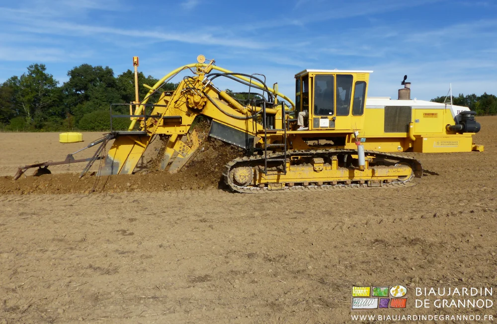 photo de la trancheuse qui avance en montant la terre et déroulant le collecteur