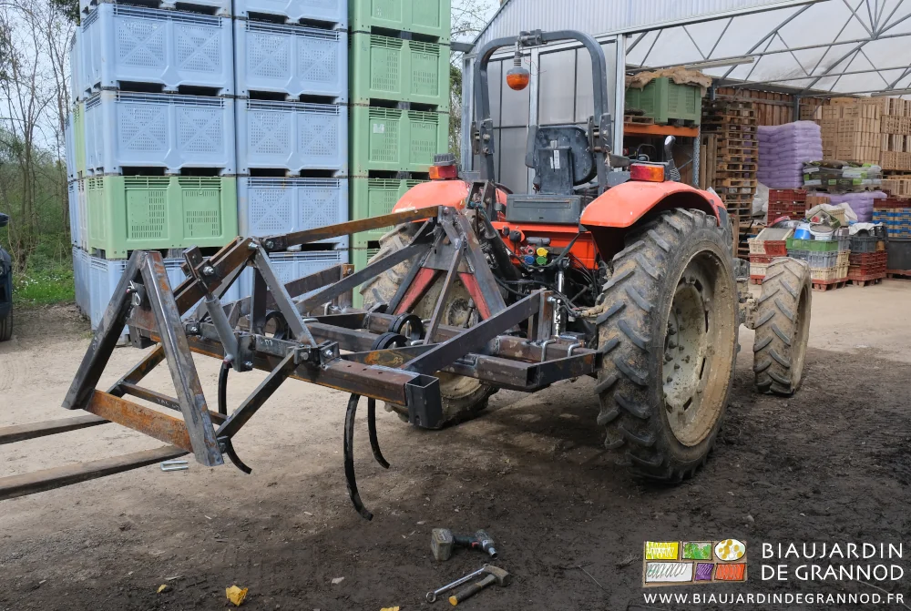 photo du montage des divers éléments de l'outil accroché au tracteur qui le teint levé