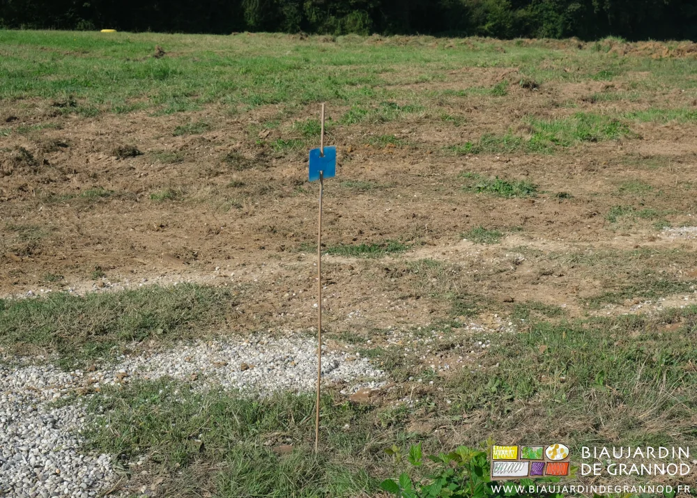 photo d'un jalon fiché en terre indiquant l'emplacement futur d'un collecteur