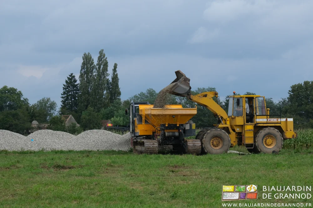 photo du chargeur remplissant la trémie au tas de gravier