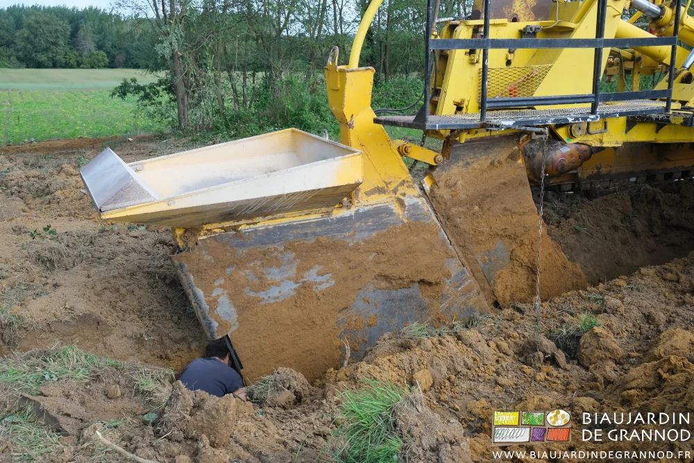 photo du caisson à gravier couplé à la goulotte de descente du drain derrière la dent de l'engin