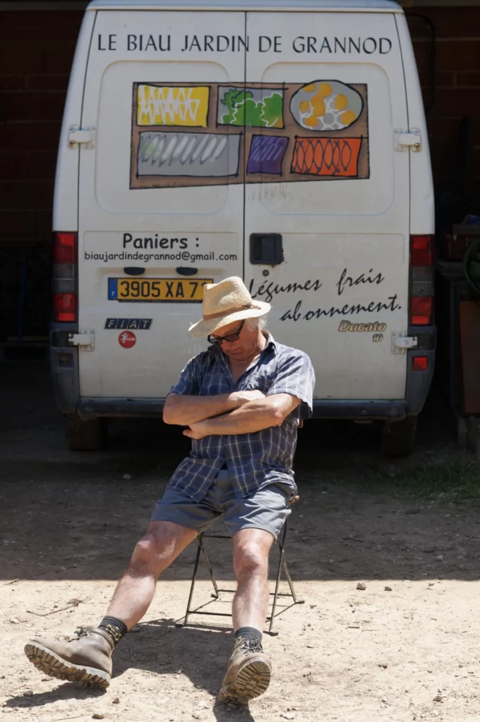 photo de Pascal en sieste sur une chaise dans la cour "au cul du fourgon" orné de son logo
