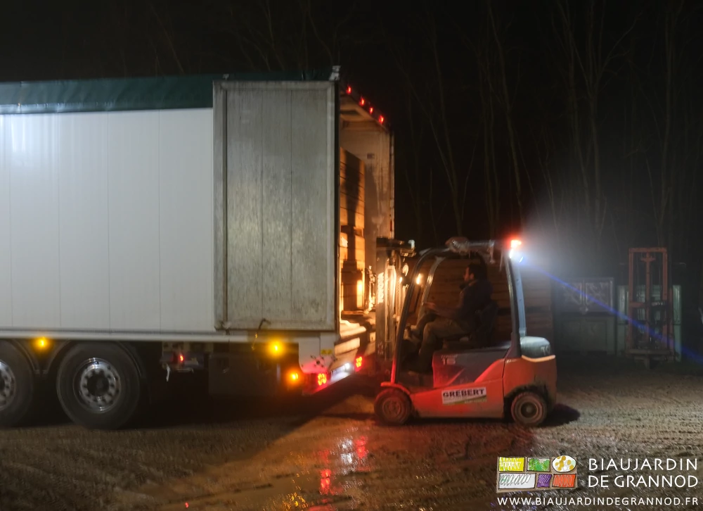 photo nocturne de Matthieu au travail avec le chariot élévateur, la remorque portes ouvertes