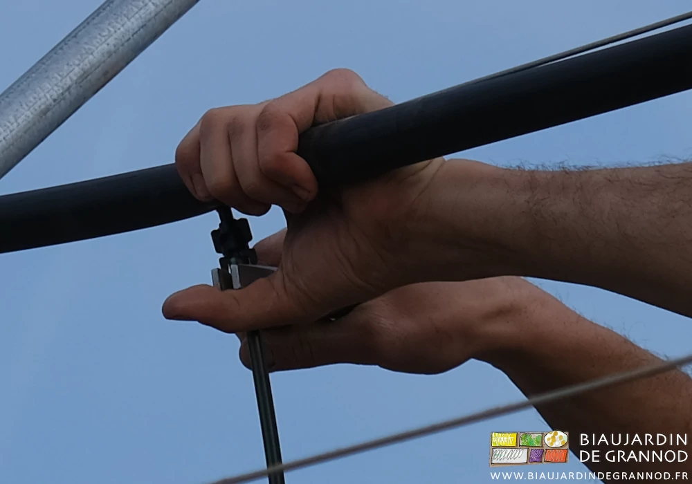 photo des mains sur la pince poussant l'embout de la cuvette dans le trou du tube d'arrosage