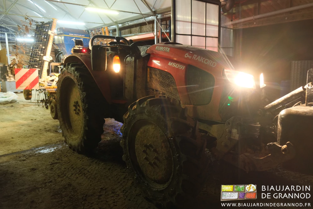 photo du tracteur en train de ranger le herse étrille dans le bâtiment chapelle