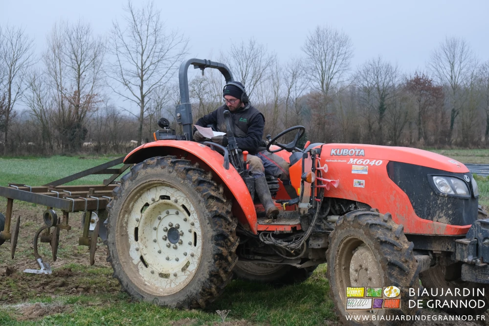 photo de Matthieu lisant ses notes au volant du tracteur attelé avec la butteuse