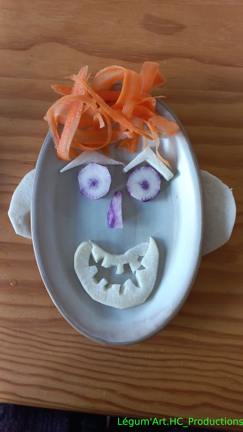 land art sur assiette par Hélène cheveu en tagliatelle de carotte, yeux radis volet bouche radis noir