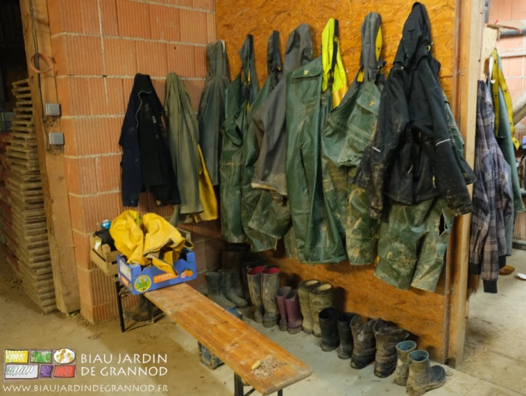 photo de la huitaine de paires de bottes et tenues imperméables rangées sous l'auvent