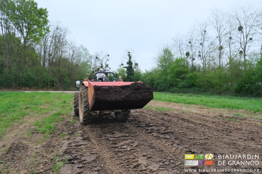 photo arrière du tracteur roulant avec sa petit benne remplie de fumir