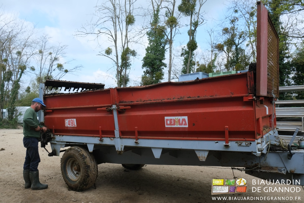 photo de Matthieu faisant une petite réparation sur l'épandeur dans la cour.