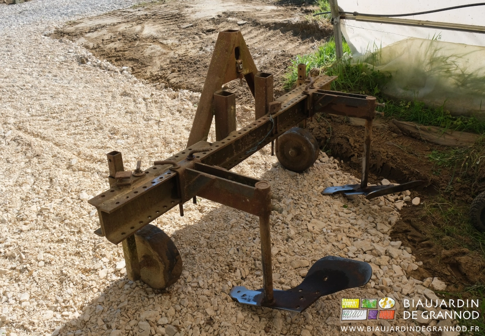 photo de l'outil rangé et ses socs de charrue prolongés par des plats en fer